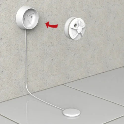 Hvit lekkasjedetektor med sensor installert på vegg, kabel ligger på gulvet mot sensorplate.