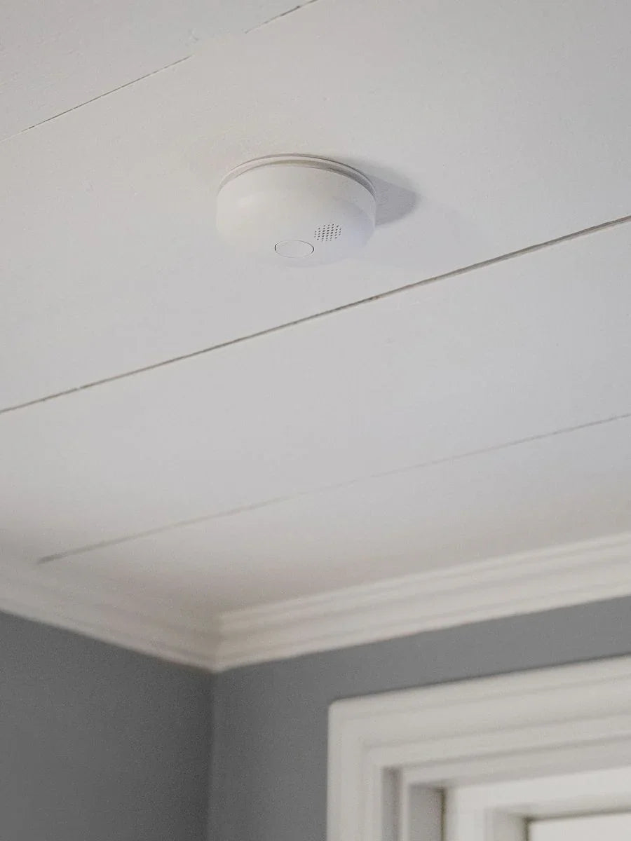 Røykvarsler montert i hvitt tak i et hjem, moderne sikkerhetsutstyr