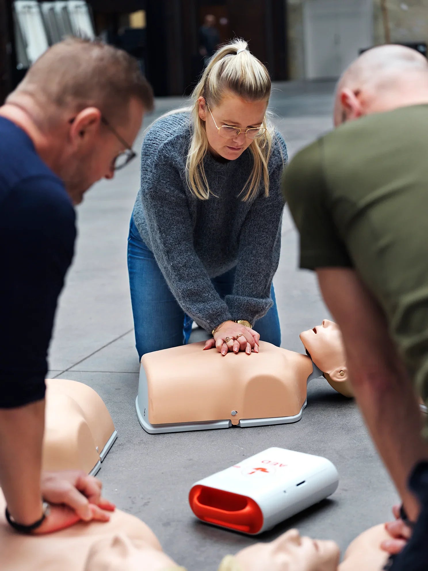 Personer trener på førstehjelp med hjerte-lunge-redning på øvingsdukker og hjertestarter