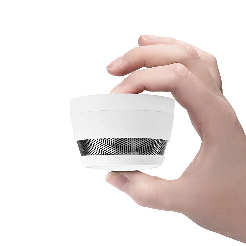 Hånd holder liten røykvarsler, brannsikkerhet, moderne design, hvit bakgrunn