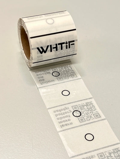 Rull med selvklebende etiketter med sirkler og QR-koder, liggende på bord