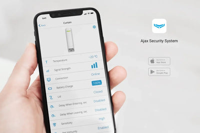 Hånd holder smarttelefon med Ajax Security System-app som viser status for sikkerhetsenhet.