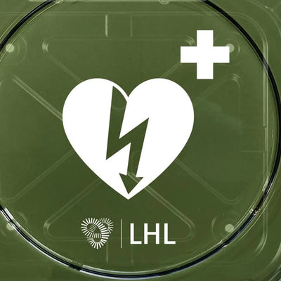 Nærbilde av hjertestartersymbol med hvitt hjerte og lyn, LHL-logo på grønn bakgrunn.